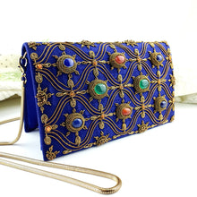 Load image into Gallery viewer, Side view of cobalt blue dupioni silk evening clutch bag embroidered with antique gold wave pattern and embellished with eight bezel set genuine gemstones including lapis lazuli, green onyx and jasper, Egyptian blue clutch, blue and gold zardozi purse.