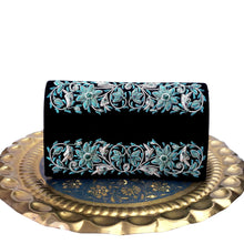 Load image into Gallery viewer, Luxury black velvet evening clutch bag hand embroidered with turquoise colored flowers and embellished with genuine turquoise and garnet gemstones displayed on a round brass platter, floral wedding clutch, black and turquoise blue zardozi purse.