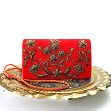 Load image into Gallery viewer, Orange velvet luxury designer evening clutch bag embroidered with flowers in antique gold color and embellished with genuine gemstones displayed on a round brass tray, wedding clutch, orange and gold zardozi purse.