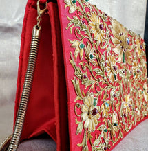 Load image into Gallery viewer, Red silk Zardozi clutch bag embroidered with gold silk flowers and inlaid with star rubies, with gold tone chain, side view
