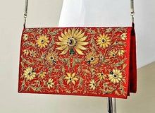 Load image into Gallery viewer, Gold and caramel colored silk flowers embroidered on vibrant red silk clutch embellished with star rubies, gold tone chain, zardozi purse.
