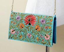 Load image into Gallery viewer, Turquoise blue silk clutch bag embroidered with multicolor silk flowers and embellished with star rubies, zardozi purse, gold tone strap.
