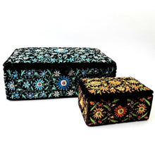 Load image into Gallery viewer, Two black velvet memory boxes, one embroidered with blue flowers and the other with orange flowers, inlaid with rubies. 
