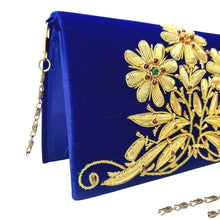 Load image into Gallery viewer, Designer hand embroidered gold flowers on blue velvet clutch bag embellished with garnet gemstones, side view.
