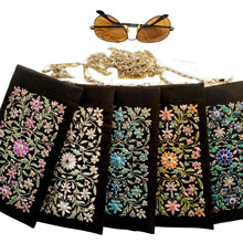 Load image into Gallery viewer, Five black silk sunglasses cases with chain embroidered with purple, white , blue, multicolor flowers.
