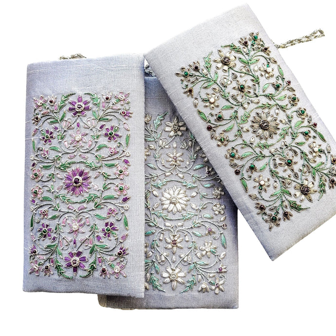 Three gray silk slim crossbody bags embroidered with purple, white or gray flowers. 