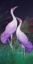 Load image into Gallery viewer, Embroidered bird wall art, two cranes with purple feathers standing in a grassy field embroidered on black velvet with an ornate border, framed, zardozi art.
