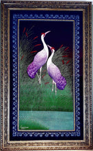 Load image into Gallery viewer, Embroidered bird wall art, two cranes with purple feathers standing in a grassy field embroidered on black velvet with an ornate border, framed, zardozi art. 
