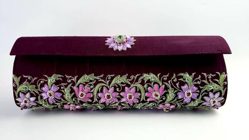 Maroon purple zardozi embroidered silk clutch bag with all over purple and pink floral design and embellished with emerald and star rubies.